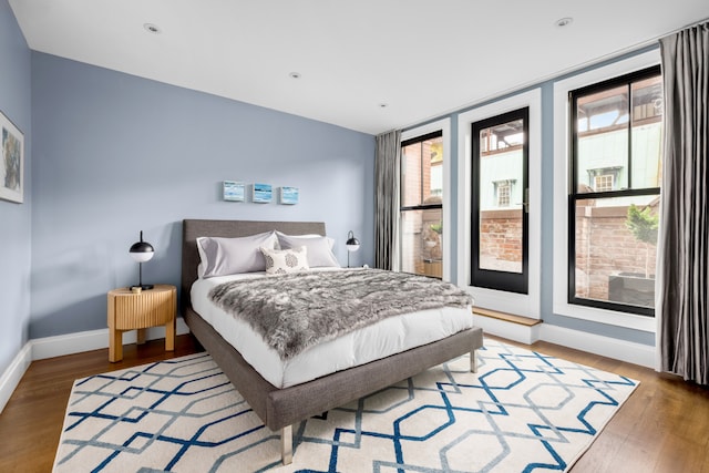 bedroom featuring multiple windows, light wood finished floors, and baseboards