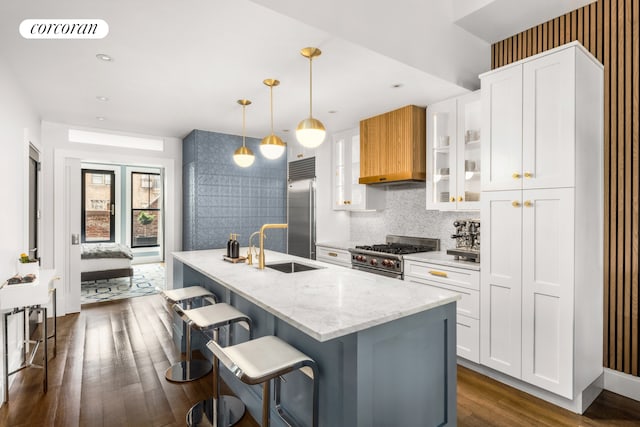 kitchen featuring high quality appliances, a sink, dark wood-type flooring, plenty of natural light, and wallpapered walls