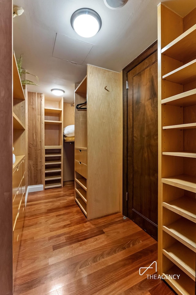 walk in closet with wood finished floors and attic access