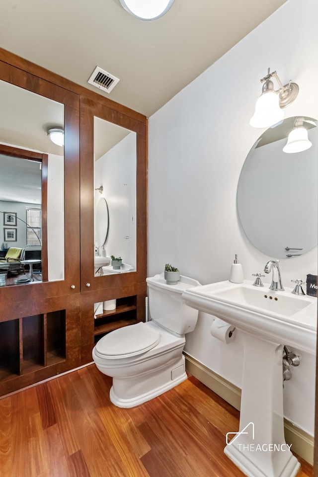 half bathroom featuring wood finished floors and toilet