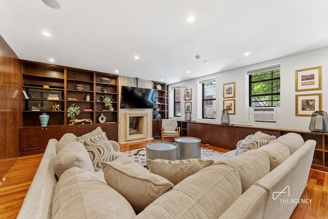 living room featuring wood finished floors, cooling unit, recessed lighting, and a fireplace