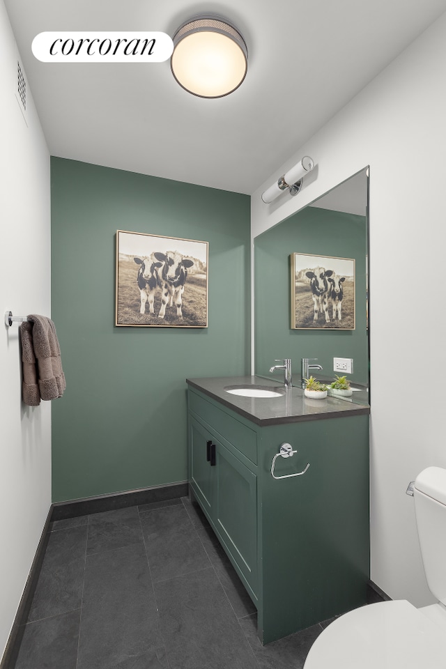 half bath featuring toilet, vanity, baseboards, and tile patterned flooring