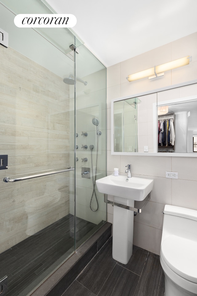 301 E 64th St Unit 7D, New York City, NY 10065 - full bath featuring tile walls, a shower stall, and toilet