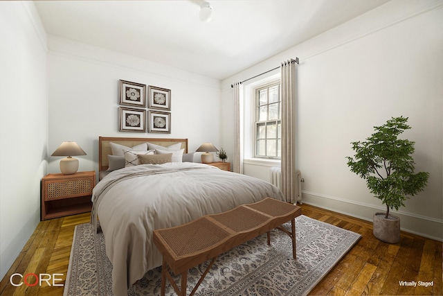bedroom with radiator, wood finished floors, and baseboards