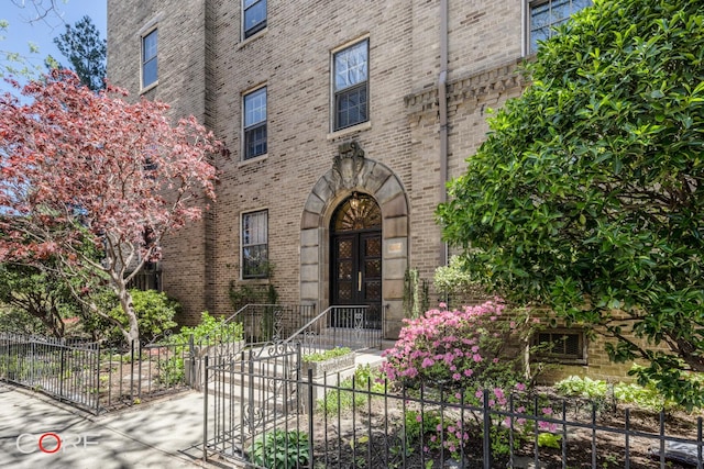 property entrance with fence and brick siding