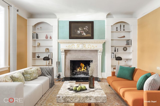 living room with a lit fireplace and built in features