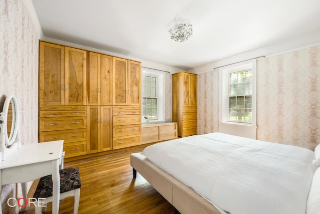 bedroom with wallpapered walls and wood finished floors