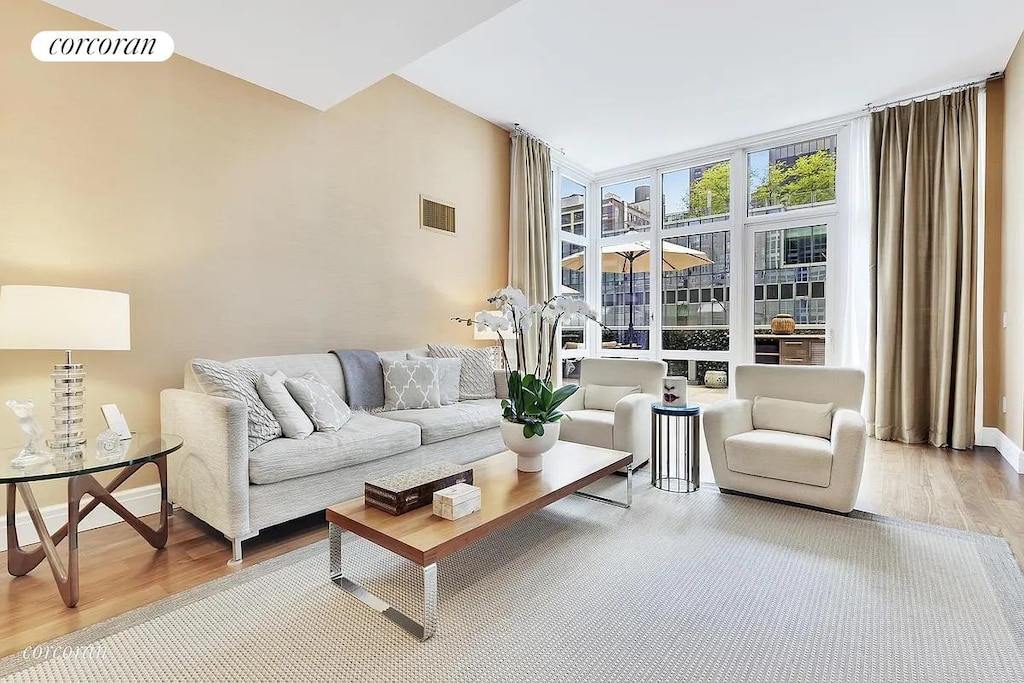living room featuring wood finished floors, a wall of windows, and baseboards