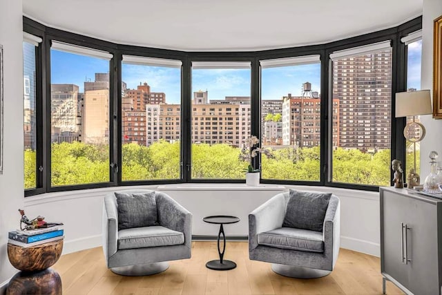 sunroom featuring healthy amount of natural light, a city view, wood finished floors, and baseboards