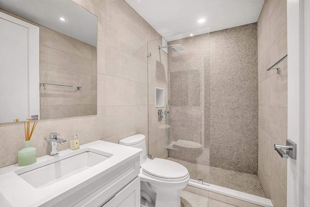 bathroom with tile walls, toilet, walk in shower, vanity, and recessed lighting