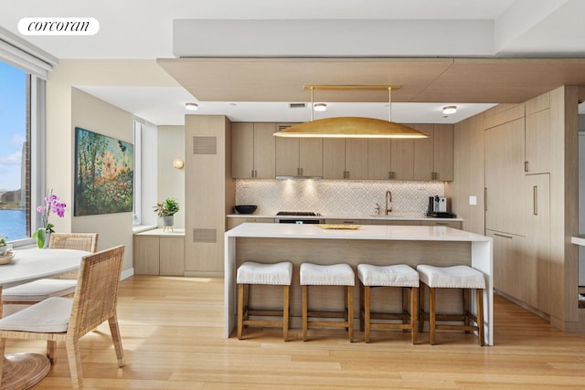 2 River Ter Unit 23C, New York City, NY 10282 - kitchen featuring backsplash, light wood finished floors, a breakfast bar, and light countertops