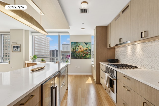 2 River Ter Unit 23C, New York City, NY 10282 - kitchen with stainless steel appliances, light wood-style floors, light countertops, and decorative backsplash