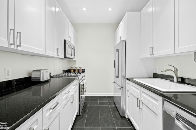 kitchen with stainless steel appliances, a sink, white cabinetry, dark tile patterned flooring, and recessed lighting