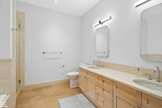 bathroom featuring a stall shower, toilet, double vanity, tile patterned floors, and baseboards