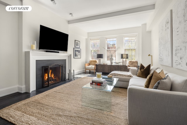 living room featuring a fireplace with flush hearth, baseboards, and wood finished floors