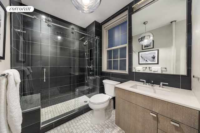full bath with toilet, a shower stall, vanity, tile walls, and tile patterned flooring