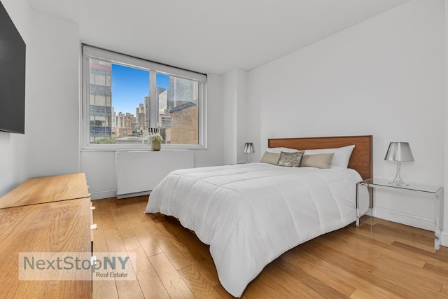 bedroom with wood finished floors and a view of city