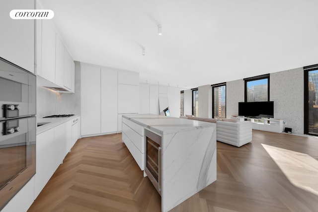 16 W 40th St Unit 29A, New York City, NY 10018 - kitchen with modern cabinets, beverage cooler, a center island, white cabinetry, and light stone counters