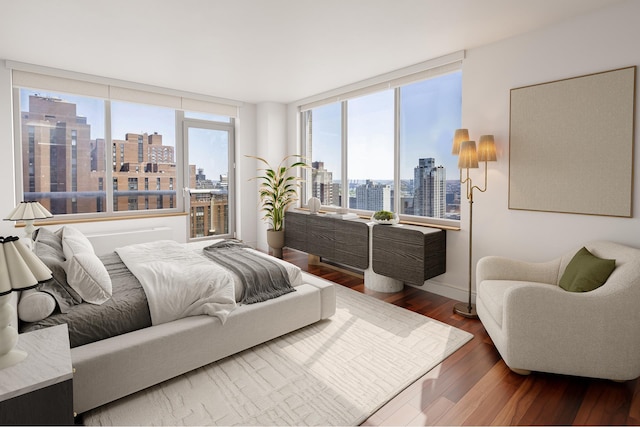 200 E 89th St Unit 27D, New York City, NY 10128 - bedroom featuring a view of skyline, wood finished floors, and baseboards