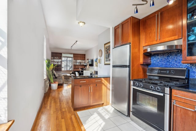 341 W 47th St Unit 4R, New York City, NY 10036 - kitchen with stainless steel appliances, wall chimney range hood, track lighting, a peninsula, and decorative backsplash