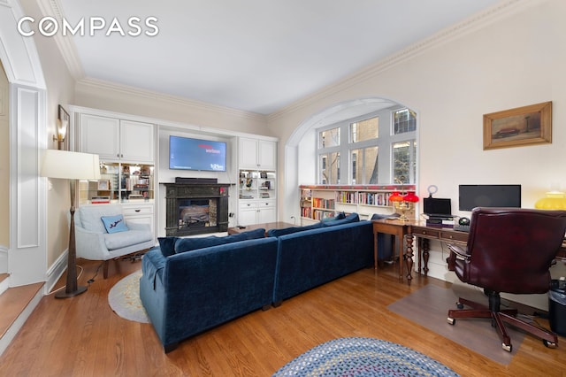 living area with crown molding, light wood-style floors, and a fireplace