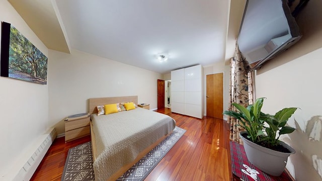 97-40 62nd Dr Unit 9K, New York City, NY 11374 - bedroom featuring a baseboard heating unit and wood finished floors