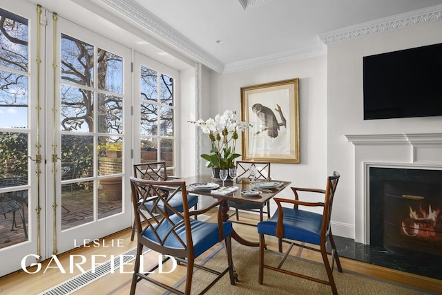 15 Sutton Place, New York City, NY 10022 - dining room featuring wood finished floors, crown molding, french doors, a warm lit fireplace, and baseboards