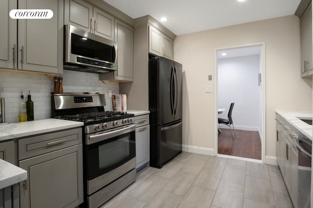kitchen featuring appliances with stainless steel finishes, gray cabinets, decorative backsplash, and recessed lighting