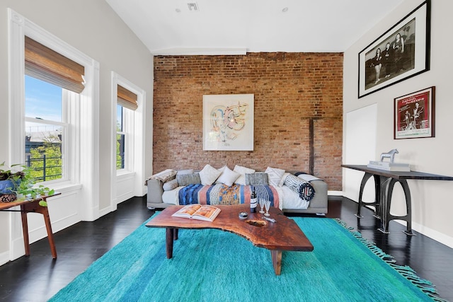 sitting room with brick wall, wood finished floors, and baseboards