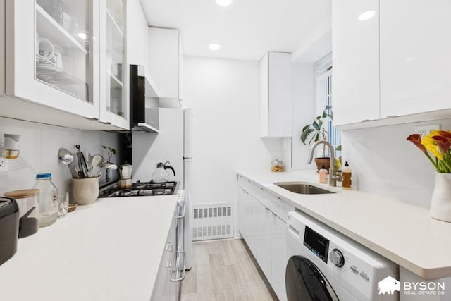 317 E 3rd St Unit 8, New York City, NY 10009 - kitchen featuring washer / clothes dryer, white cabinetry, a sink, light countertops, and recessed lighting