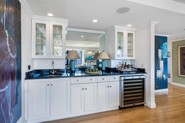 indoor wet bar with wine cooler, ornamental molding, light wood-style floors, recessed lighting, and baseboards