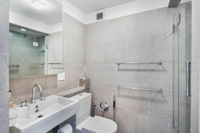 full bath featuring a sink, toilet, a stall shower, and tile walls