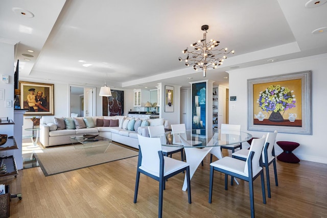dining room with a tray ceiling, wood finished floors, a chandelier, baseboards, and recessed lighting
