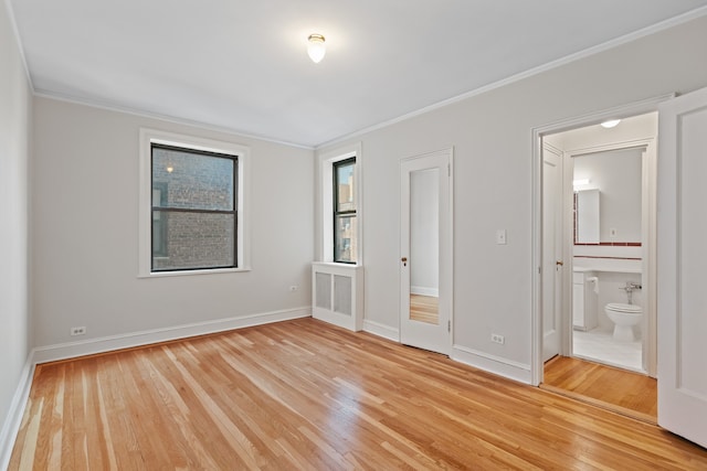 unfurnished bedroom featuring light wood-style floors, ornamental molding, baseboards, and ensuite bathroom