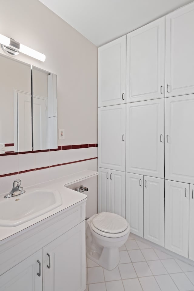 bathroom featuring toilet, vanity, tile patterned floors, and tile walls