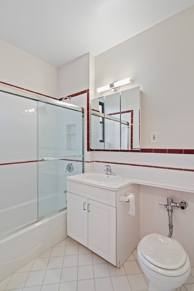 bathroom with tile walls, tile patterned flooring, vanity, shower / bath combination with glass door, and toilet