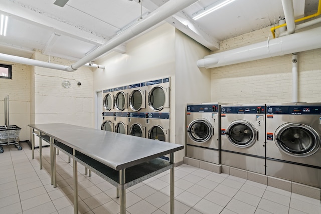 communal laundry room featuring washing machine and clothes dryer, estacked washer and dryer, and tile patterned flooring