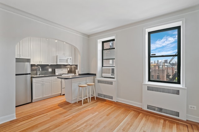 kitchen with white appliances, radiator, a sink, and arched walkways