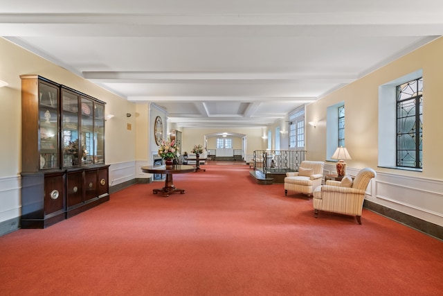 sitting room with carpet floors, beam ceiling, coffered ceiling, a wainscoted wall, and a decorative wall