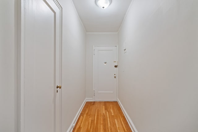 doorway with light wood finished floors, crown molding, and baseboards