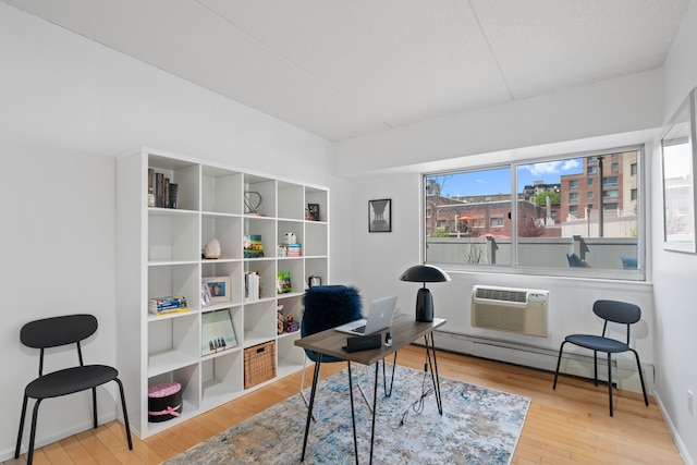 office with a baseboard radiator, a wall mounted AC, and wood finished floors