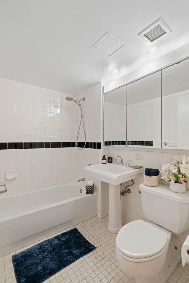 bathroom featuring toilet, tile patterned flooring, bathtub / shower combination, and tile walls
