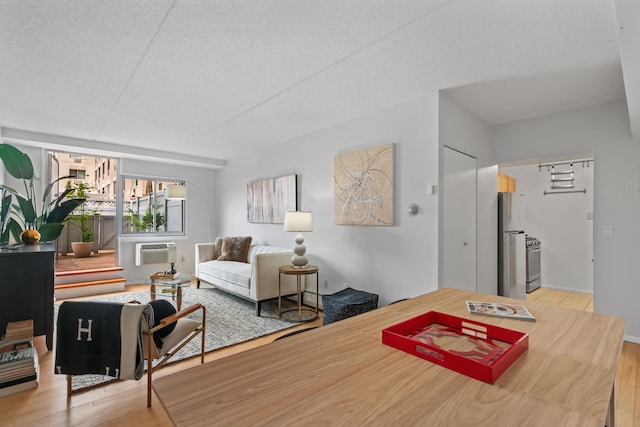 dining space featuring light wood-style flooring, a wall unit AC, and a textured ceiling