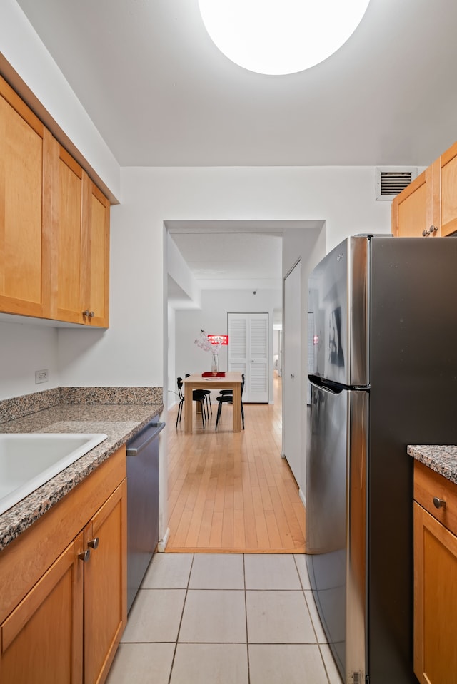 kitchen featuring stainless steel appliances, light tile patterned flooring, light countertops, and a sink