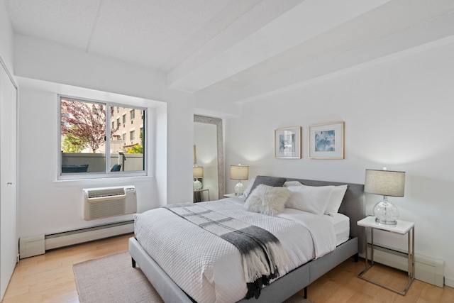 bedroom with a baseboard radiator, a wall unit AC, and wood finished floors
