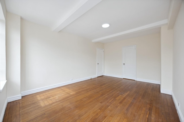 unfurnished room with beam ceiling, hardwood / wood-style flooring, and baseboards