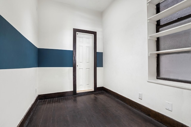 spare room featuring wood finished floors and baseboards