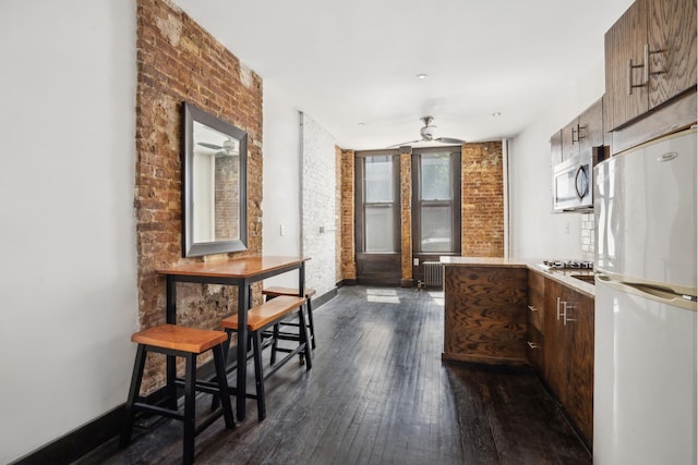 kitchen with white appliances, dark wood-style flooring, ceiling fan, radiator heating unit, and light countertops