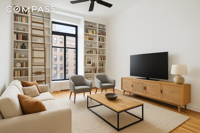 living room featuring wood finished floors, a ceiling fan, ornamental molding, and baseboards