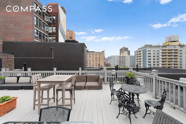 wooden terrace with a view of city and an outdoor hangout area